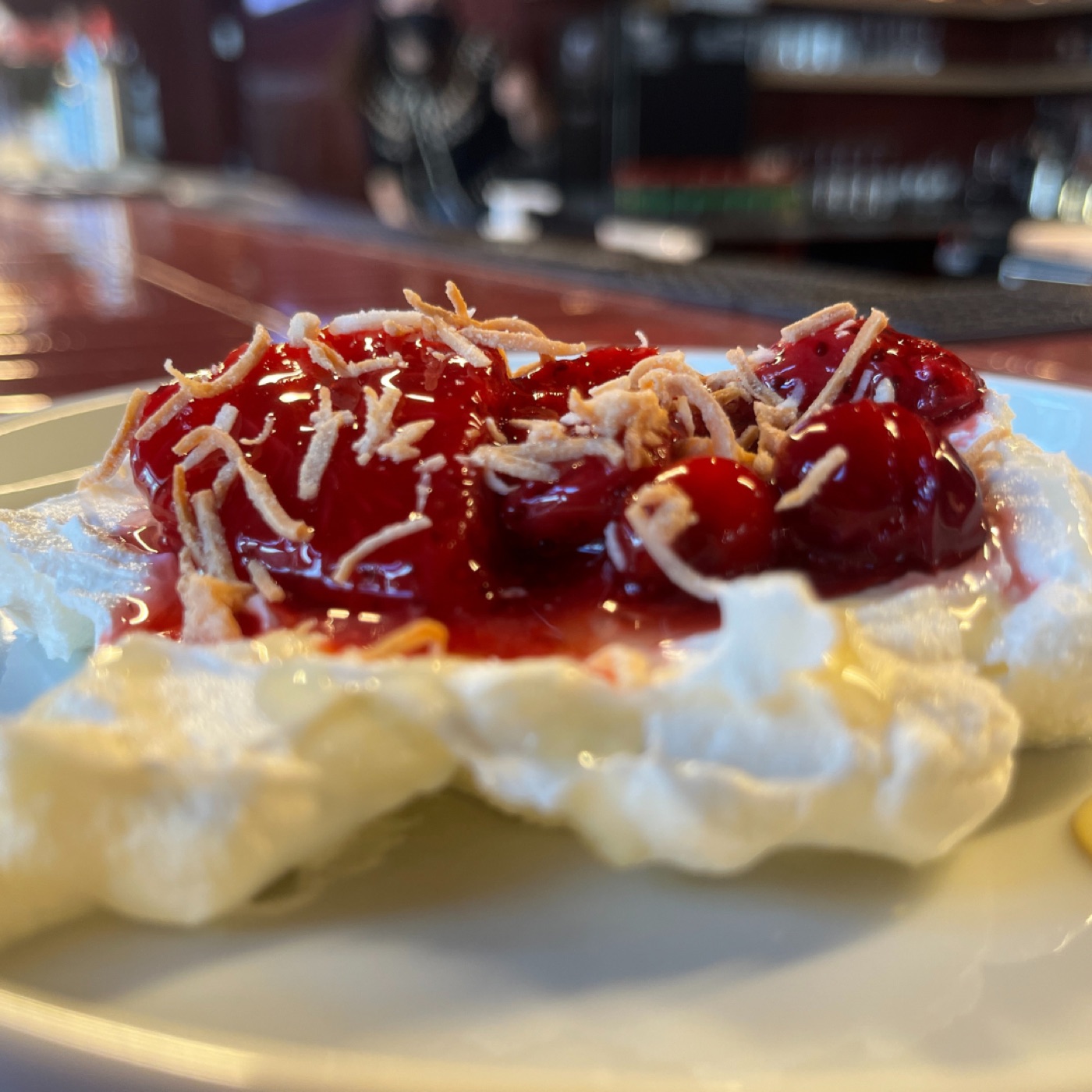 Pavlova topped with cherries and toasted coconut.